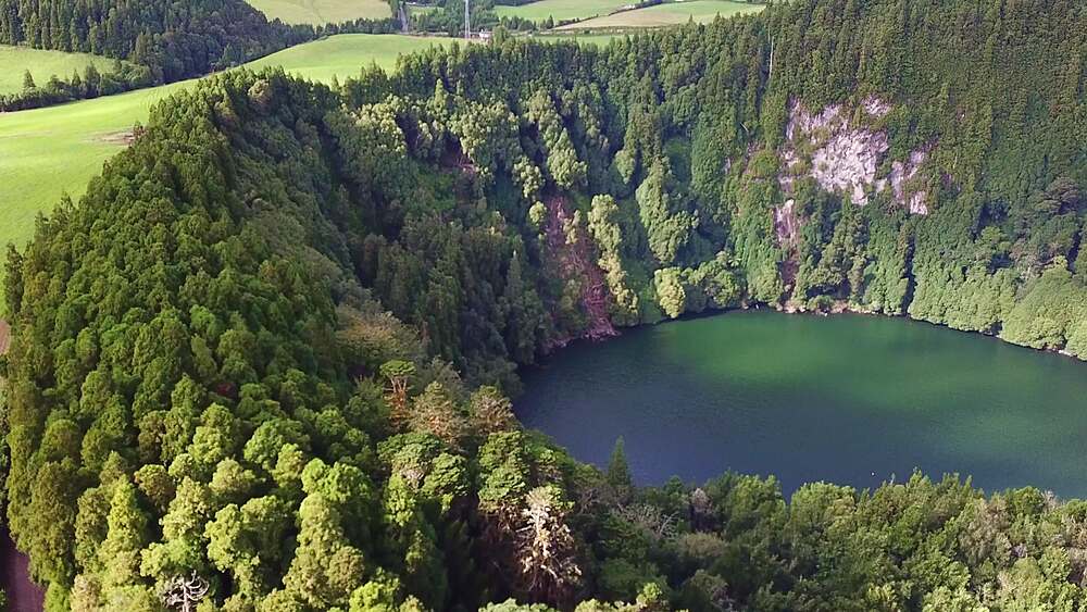 Aerial reveal of an Empadadas crater lake set in cryptomeria forest, Sao Miguel, Azores, Portugal