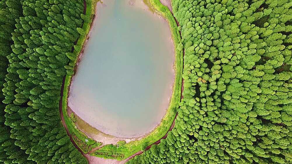 Bird's-eye descent across the twin Empadadas lakes and their forested causeway, Sao Miguel, Azores, Portugal