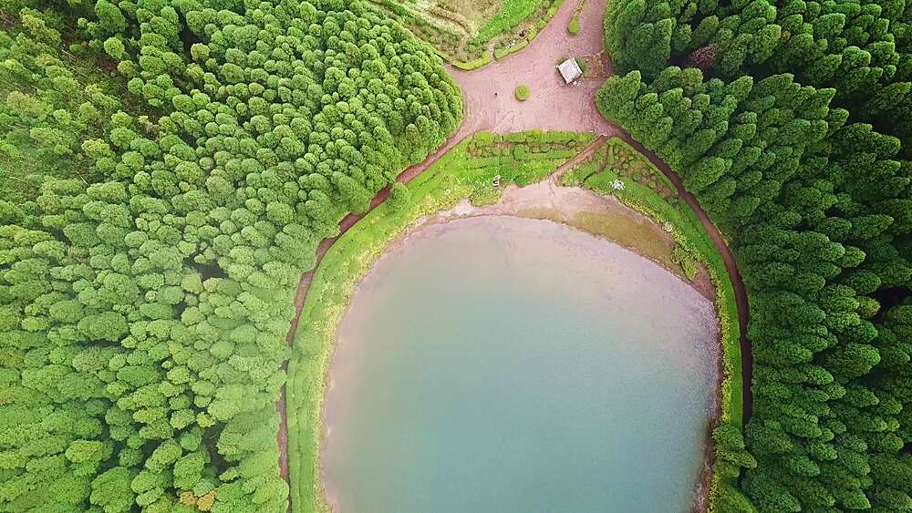 Descending drone push-in toward a still Empadadas crater lake,  Sao Miguel, Azores, Portugal