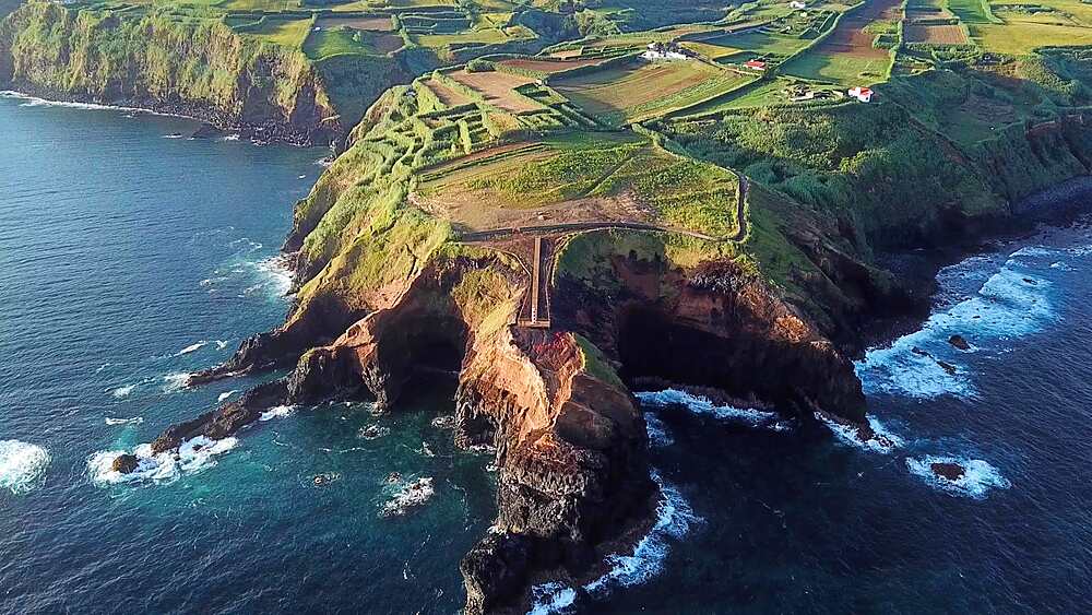 Aerial pullback over clifftop farmland behind Farolim dos Fenais da Ajuda, cinematic opener for Sao Miguel, Azores