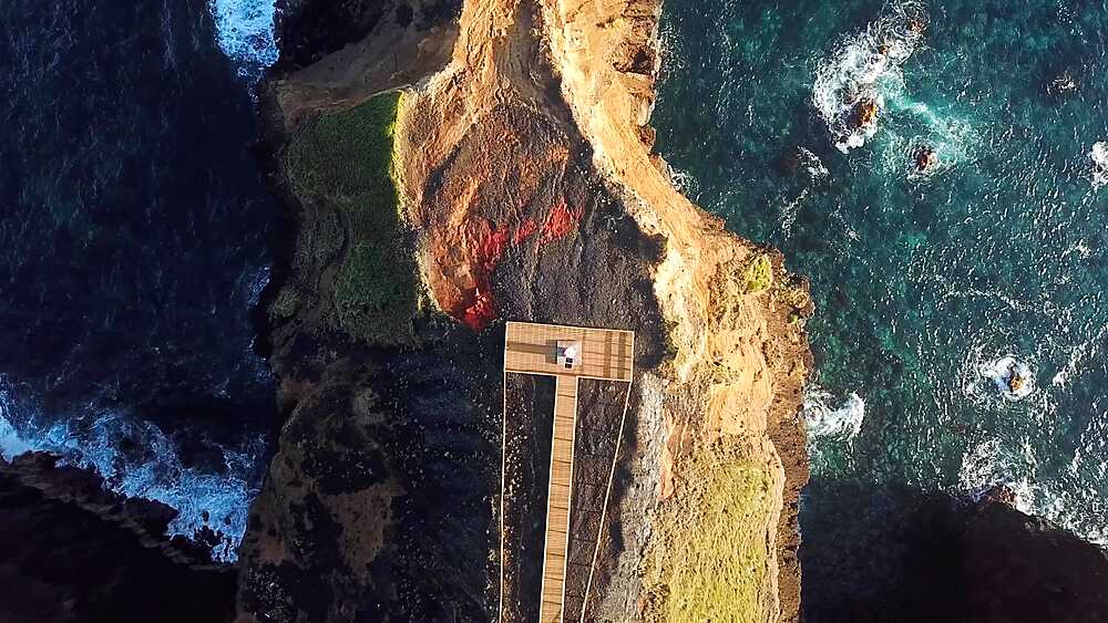 Descending drone over boardwalk to Farolim dos Fenais da Ajuda lighthouse, title sequence opener, Sao Miguel, Azores