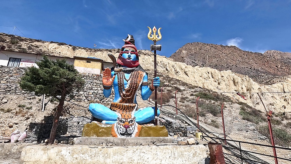 Orbiting Painted blue Shiva statue trident tiger shrine hillside Jomsom Mustang Nepal Himalaya