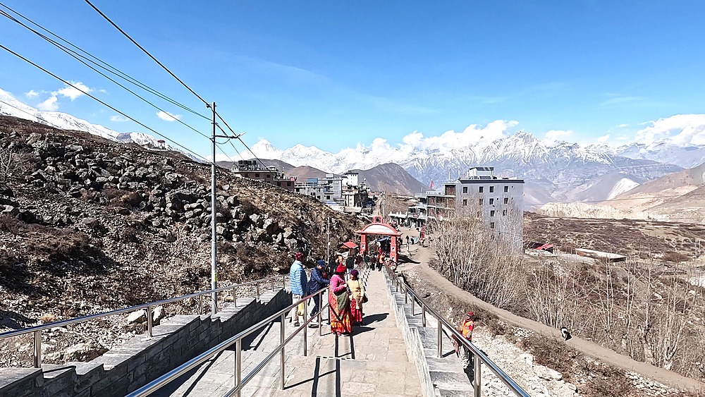 Stone pathway pilgrims village red gate snow peaks Muktinath Mustang Nepal Hindu pilgrimage