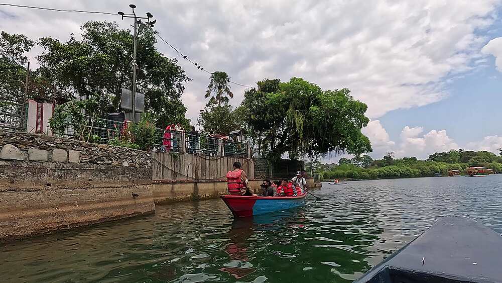 Tal Barahi island temple seen from the water with a boat leaving on Phewa Lake, Pokhara, Nepal