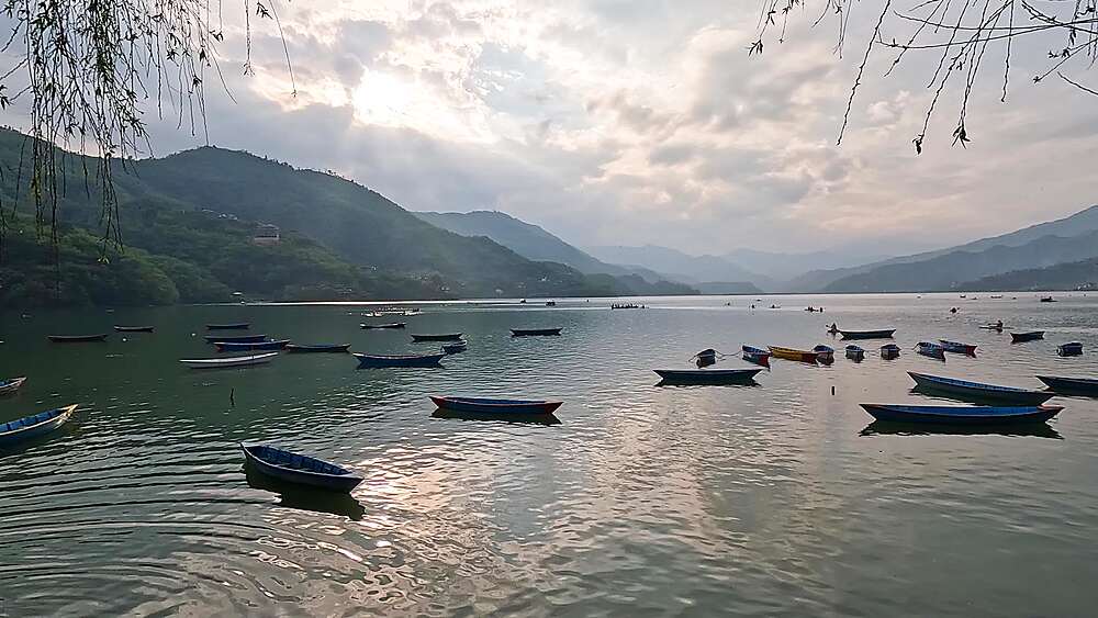 Pan across wooden boats scattered on Phewa Lake under an overcast sky, Pokhara, Nepal
