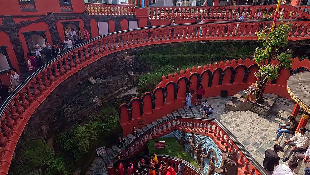 Pan following the curving red spiral staircase into Gupteshwor Mahadev Cave temple, Pokhara, Nepal