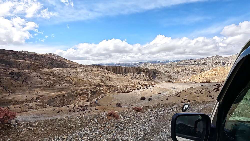 Dusty 4WD road winding past eroded cliffs near Yara Gaun, Upper Mustang, Nepal
