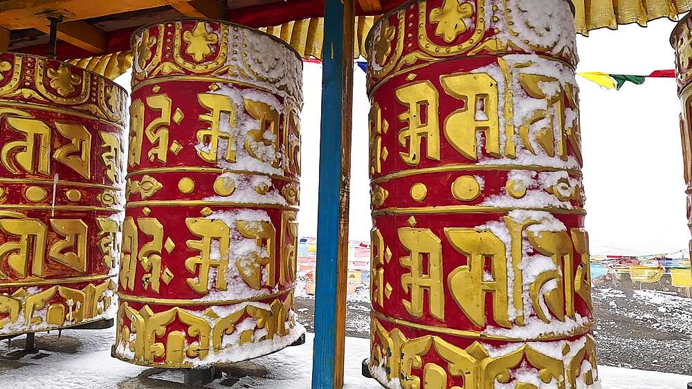 Snowy Tibetan prayer wheels with gold mantras at Lo Gekar (Ghar Gompa), Upper Mustang, Nepal