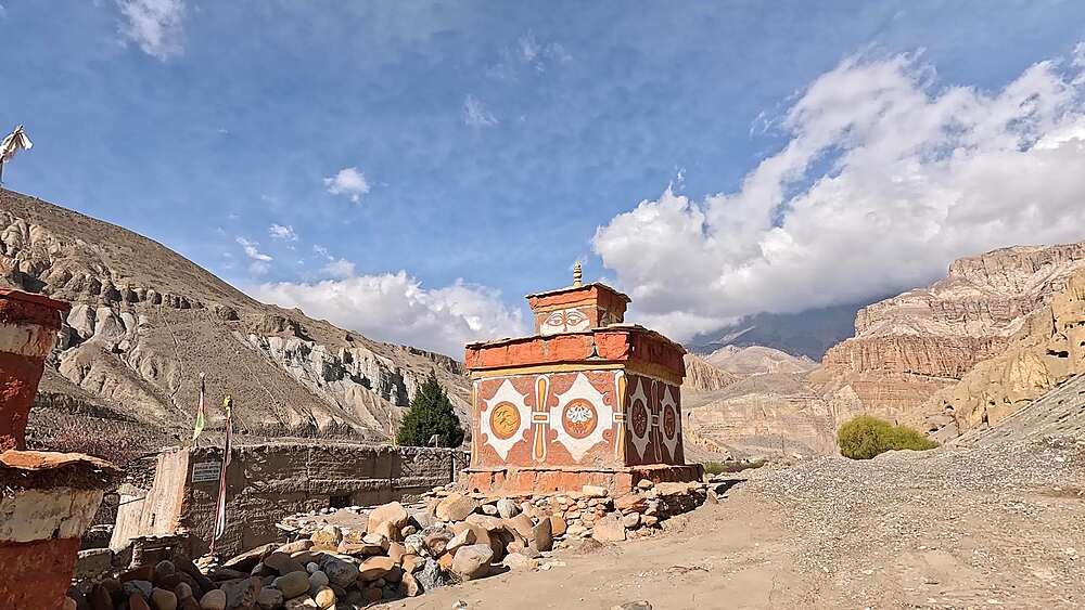 Slow approach to painted chortens with Buddha eyes and mandala motifs against eroded cliffs, Chhusang, Upper Mustang, Nepal