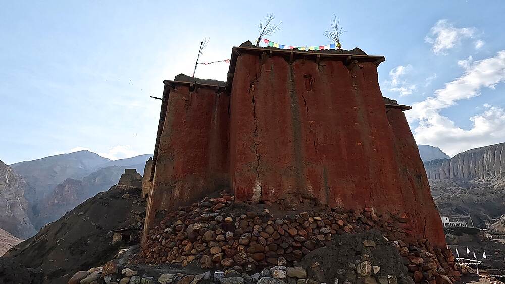 Wide opening shot of Tetang monastery with red walls and canyon landscapes in the background, Tetang, Upper Mustang, Nepal