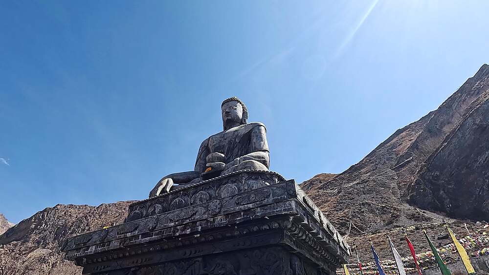 Orbiting half circle shot of Sakyamuni Buddha statue against blue sky, Muktinath, Nepal