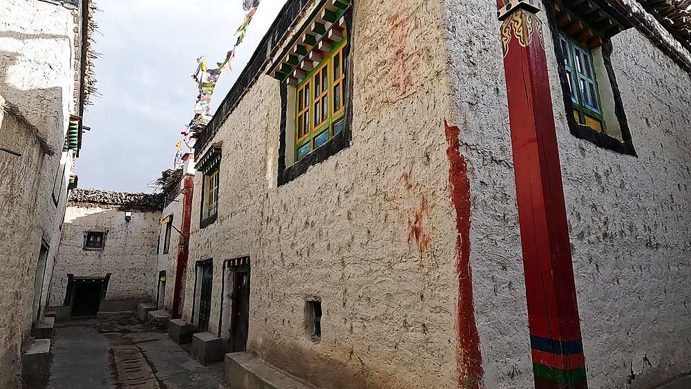 Narrow walled alley whitewashed houses carved window Lo Manthang Upper Mustang Nepal