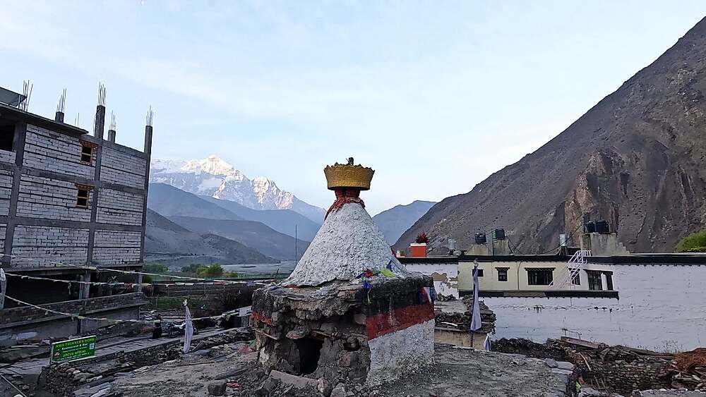 Monastery stupa with golden crown at sunrise, snow-capped peak backdrop, sacred site Nepal