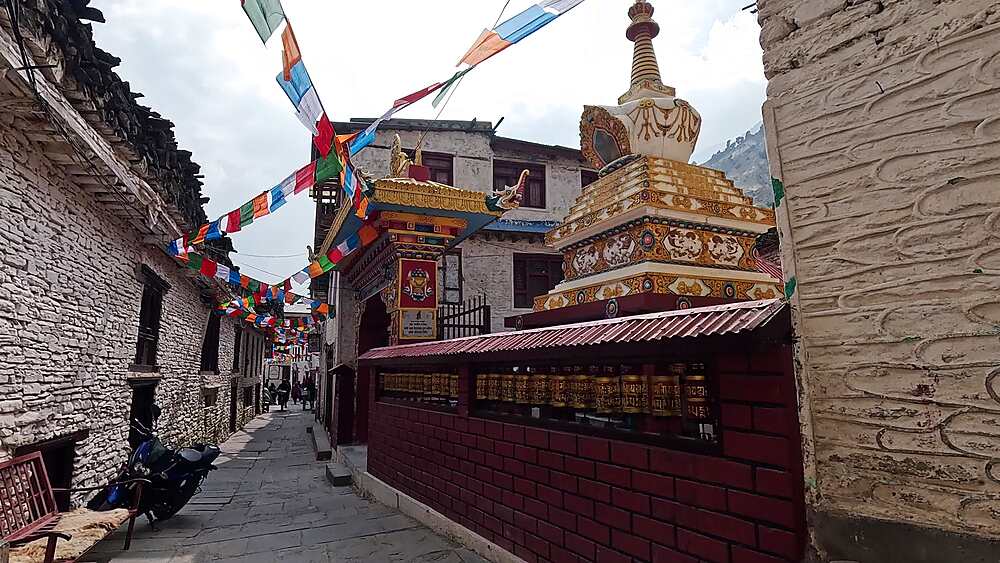 Village street with Buddhist stupa, prayer flags, white stone buildings Marpha Nepal