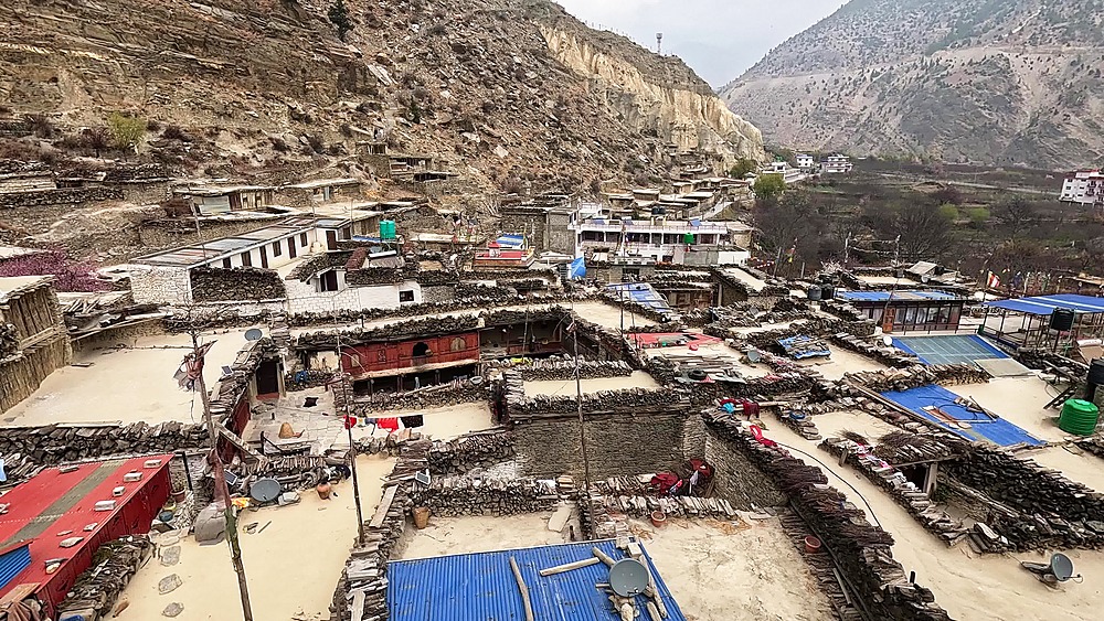 Aerial view Marpha settlement, rooftops, prayer flags, dry valley mountains Nepal