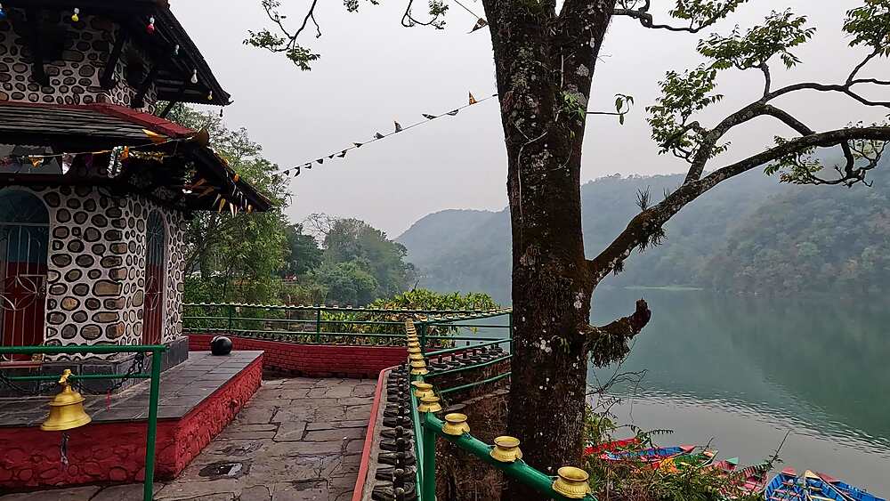 Shiva Mandir Gaurighat stone temple with red base, prayer flags, overlooking Phewa Lake, Pokhara