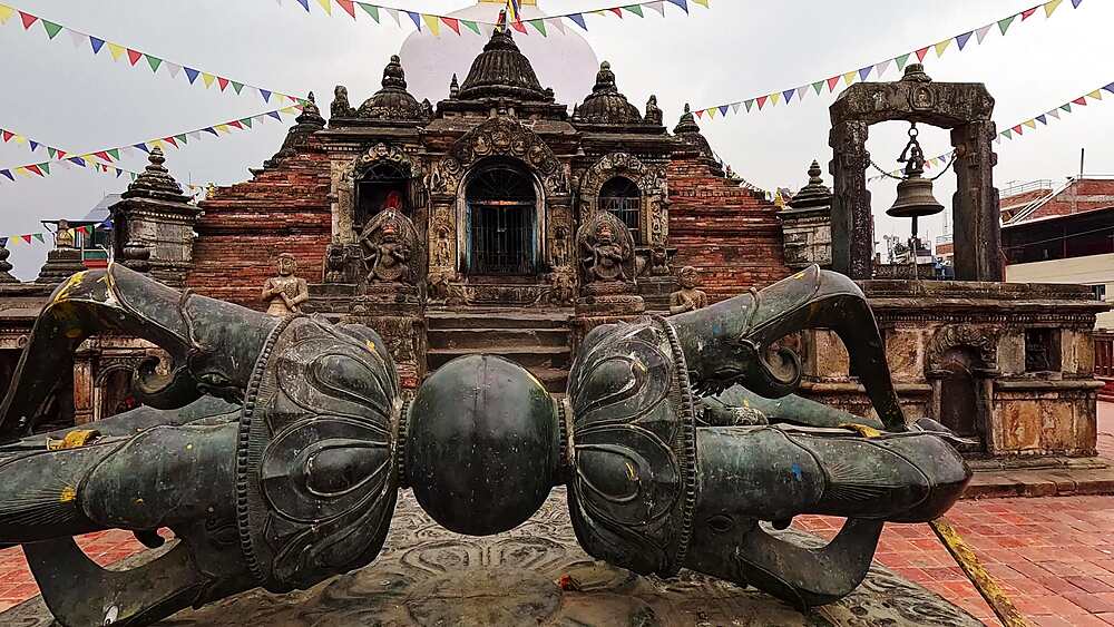 Chilancho Stupa compound, large bronze vajra thunderbolt ritual object on plinth with temple facade behind, Kirtipur, Nepal