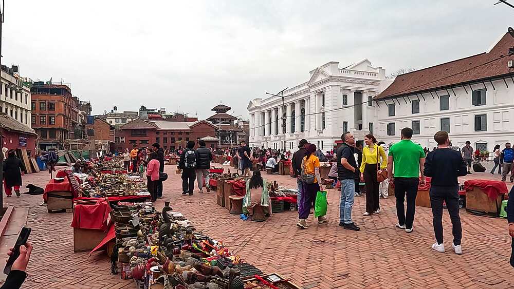 Kathmandu Durbar Square handicraft market, vendors with bronze and brass wares, Gaddi Baithak neoclassical facade, Nepal