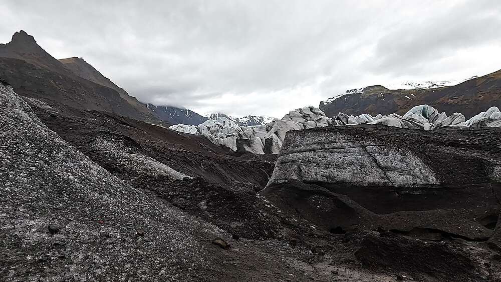 Svinafellsjokull on-glacier jagged ash-streaked seracs with blue ice cores and crevasse hole, Iceland
