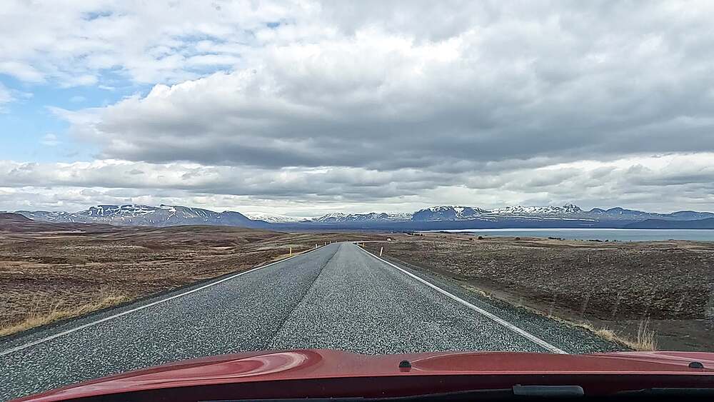 Dashcam POV on straight Route 36 toward Thingvellir with Lake Thingvallavatn right and snow mountains ahead, Iceland