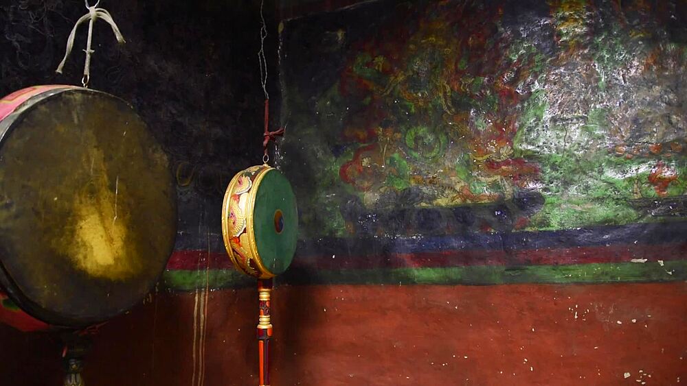 Ritual drums and ornate fittings against painted murals inside a monastery at Lo Manthang, Upper Mustang, Nepal