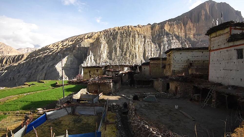 Pan over barley fields and the traditional village of Tetang beneath layered cliffs, Upper Mustang, Nepal