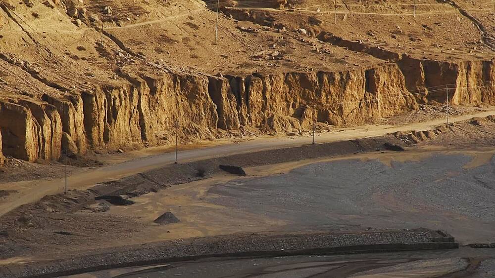 Close pan over a canyon road cut into eroded cliffs above the Kali Gandaki riverbed, Chele, Upper Mustang, Nepal