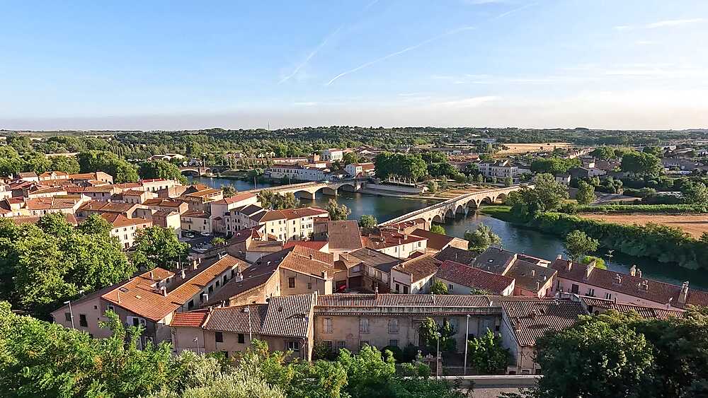 Panorama view from jardin Eveques over the old town roofs of Beziers in evening light and river Orb with roman bridge, Beziers, France
