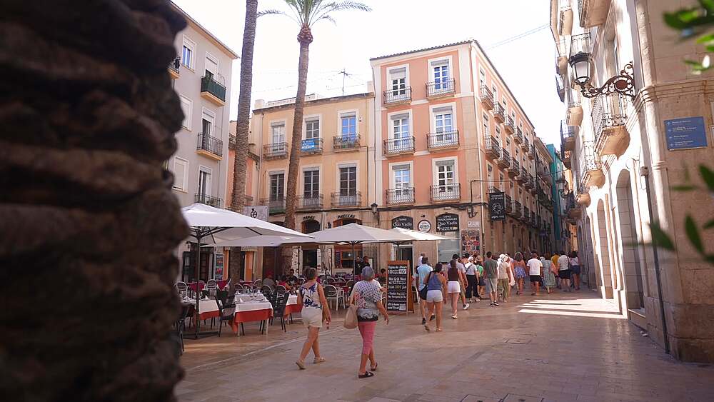 View of tourists and restaurants in Placa de la Santissima Fac on a sunny day in Alicante, Alicante, Costa Blanca, Spain, Europe