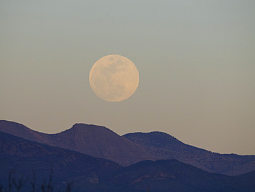 The full moon rising in the east over Whitewater Draw State Wildlife Area near McNeal in southeast Arizona, USA.