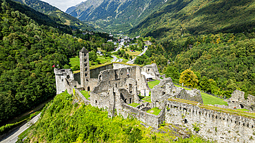 Aerial view shows Mesocco castle ruins surrounded by mountains and greenery in Switzerland