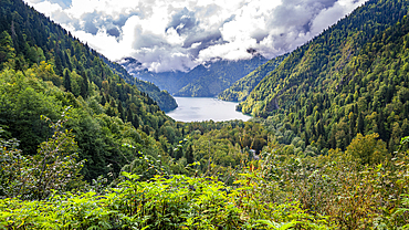 View from the overlook of Ritsa Lake showing mountains and lush forests in a natural landscape with clouds above
