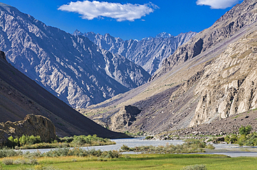 Mountains rise sharply above a river in Bartang Valley capturing the rugged beauty of Tajikistan's landscape
