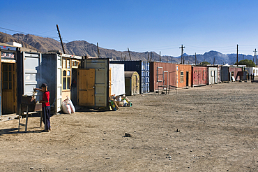 Container market in Murgab with vendors preparing goods and engaging with customers amid mountains and clear sky in Tajikistan