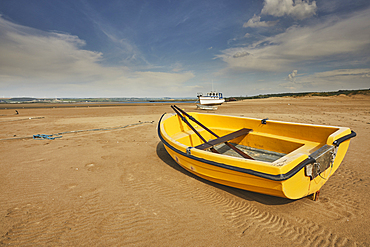A beached dinghy at low tide, at Crow Point, on the shore of the Taw and Torridge estuary, near Barnstaple, Devon, Great Britain.