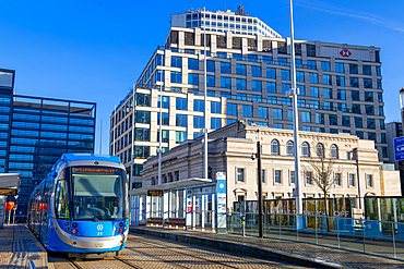 Urbos 3 tram arrives at Centenary Square during a clear day in Birmingham's urban landscape