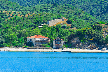 Abandoned Chomitsa Arsanas boat harbor and the Mount Athos border wall along the Aegean shoreline near Ouranoupolis, Greece.