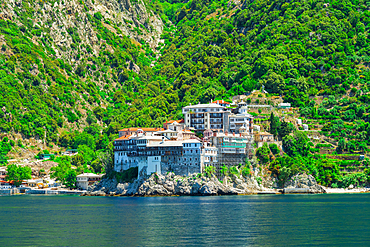 Osiou Gregoriou Monastery perched on rocky cliffs over the Aegean Sea on the forested Mount Athos peninsula, Greece.