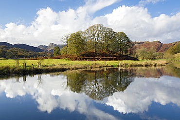 View across the tranquil waters of the River Brathay to the distant Langdale Pikes, autumn, Elterwater, Lake District National Park, Cumbria, England, UK