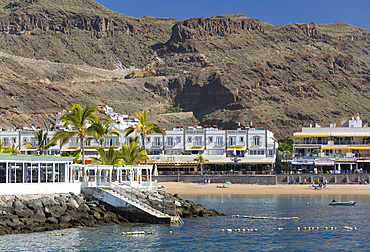 View across harbour entrance to the beach and towering volcanic cliffs behind the village, Puerto de Mogan, Gran Canaria, Canary Islands, Spain<br />1310-465 View across harbour entrance to the beach and towering volcanic cliffs behind the village, Puerto de Mogan, Gran Canaria, Canary Islands, Spain