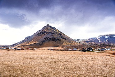 Sharply pointed volcanic peak above flat autumn moorland with farm buildings below, Arnarstapi, Sn&aelig;fellsnes Peninsula, West Iceland