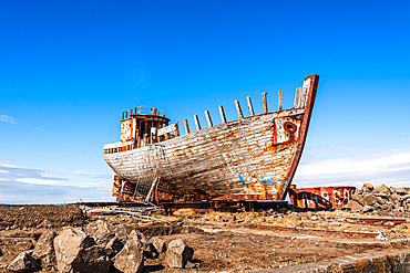 Derelict fishing vessel H&ouml;frungur AK-91 beached on the rocky shore at Akranes under a bright blue sky, West Iceland
