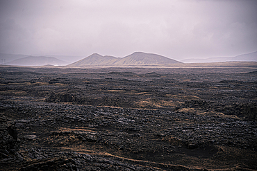 Mt. Thorbjorn (Thorbjarnafell), flat-topped hyaloclastite tuya volcano rising above vast black lava field under overcast sky, near Grindavik, Reykjanes Peninsula, Southwest Iceland, Iceland, Europe.
