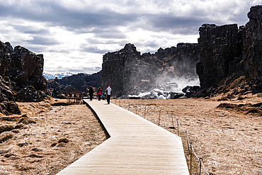 Walking through Almannagj rift gorge on wooden boardwalk at Thingvellir National Park in Iceland