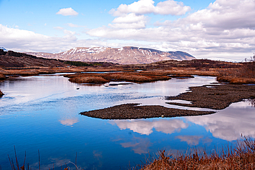Tranquil reflections on &THORN;ingvallavatn (Lake Thingvallavatn), Iceland's largest natural lake, within &THORN;ingvellir National Park. Snow-dusted mountains mirrored in still water, Golden Circle route.