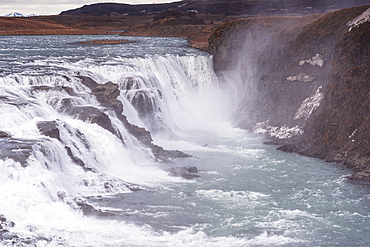 The mighty Gullfoss waterfall thundering over two tiers into a misty canyon, Iceland. Iconic Golden Circle cascade on the glacial Hv&iacute;t&aacute; river framed by rugged cliffs.