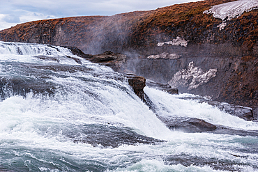 Gullfoss, Golden Circle, South Iceland. Powerful cascades thundering over rocky tiers with mist rising into the air. Iconic waterfall, raw nature and the elemental power of the glacial Hv&iacute;t&aacute; river.