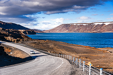 Kleifarvatn, Reykjanes Peninsula, Iceland. Lone car on Route 42 winding along the deep blue lake beneath rugged volcanic mountains. Road trip, scenic drive and adventure travel through a dramatic, unspoiled volcanic landscape on the Mid-Atlantic Ridge.<br />1372-3943 Kleifarvatn, Reykjanes Peninsula, Iceland. Lone car on Route 42 winding along the deep blue lake beneath rugged volcanic mountains. Road trip, scenic drive and adventure travel through a dramatic, unspoiled volcanic landscape on the Mid-Atlantic Ridge.