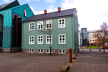 Reykjavik, Iceland. A green timber building with white-framed windows in the historic city centre under a bright blue sky. Charming Nordic architecture, heritage and vibrant capital culture in Iceland.
