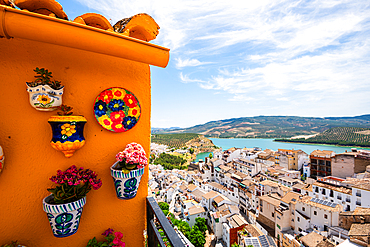 Iznájar, Córdoba, Andalusia, Spain. Colourful painted ceramic plates and flowerpots on an ochre wall above the whitewashed village and reservoir. Andalusian ceramic art and scenic pueblo blanco view<br />1372-3995 Iznájar, Córdoba, Andalusia, Spain. Colourful painted ceramic plates and flowerpots on an ochre wall above the whitewashed village and reservoir. Andalusian ceramic art and scenic pueblo blanco view
